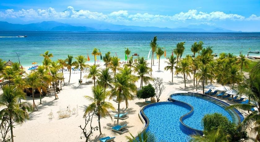 Visitors relaxing on sunbeds, others swimming in a curved pool and walking the white-sand beach at Nusa Lembongan.