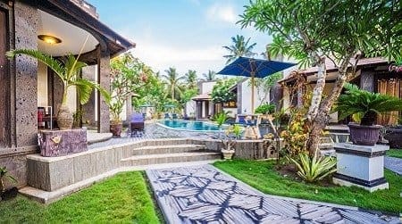 Sunlit Nusa Lembongan resort with central pool, steps, umbrella-shaded loungers, tropical villas and a garden path.