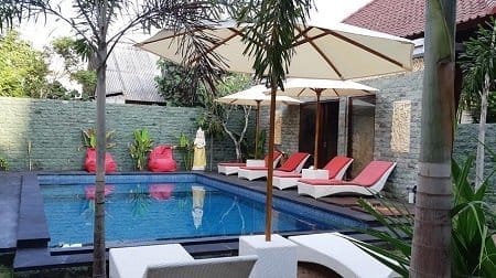 Empty sun loungers and umbrellas beside a calm pool at a villa in Nusa Lembongan.