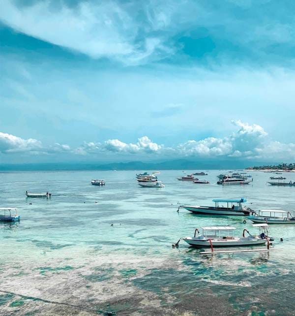 The experience of lifetime 1 Several small motorboats anchored and bobbing in shallow turquoise water off Nusa Lembongan under a bright blue sky.